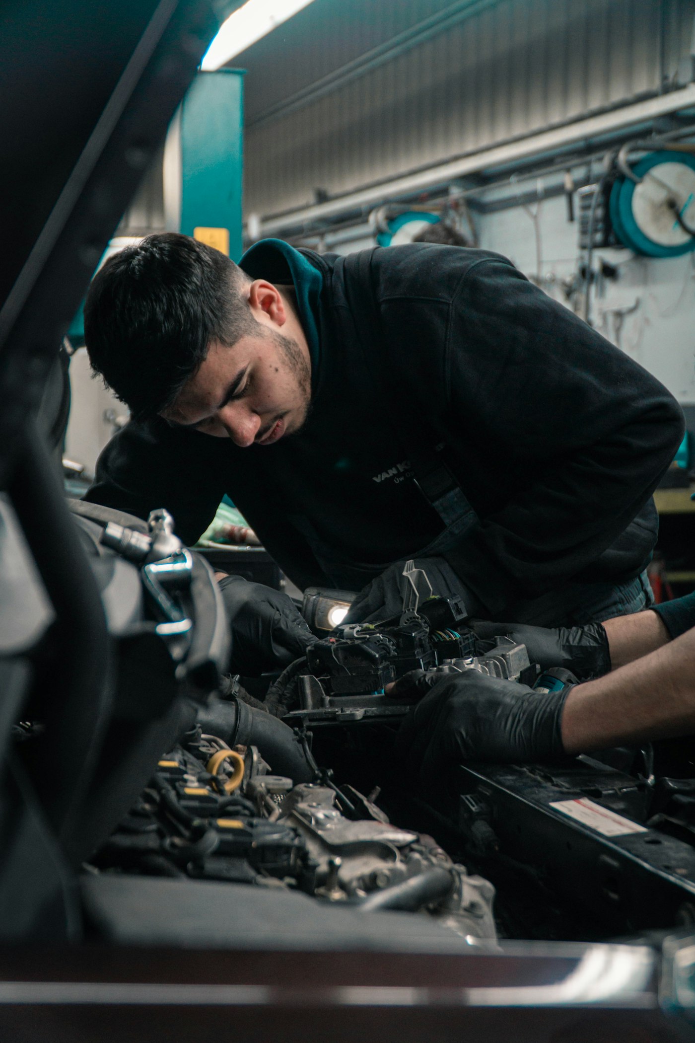 Mechaniker prüft Leitungen im Motorraum